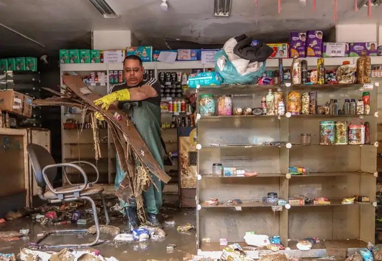 Comerciante retira entulho de loja invadida por água das chuvas em Porto Alegre (Rafa Neddermeyer/Agência Brasil)