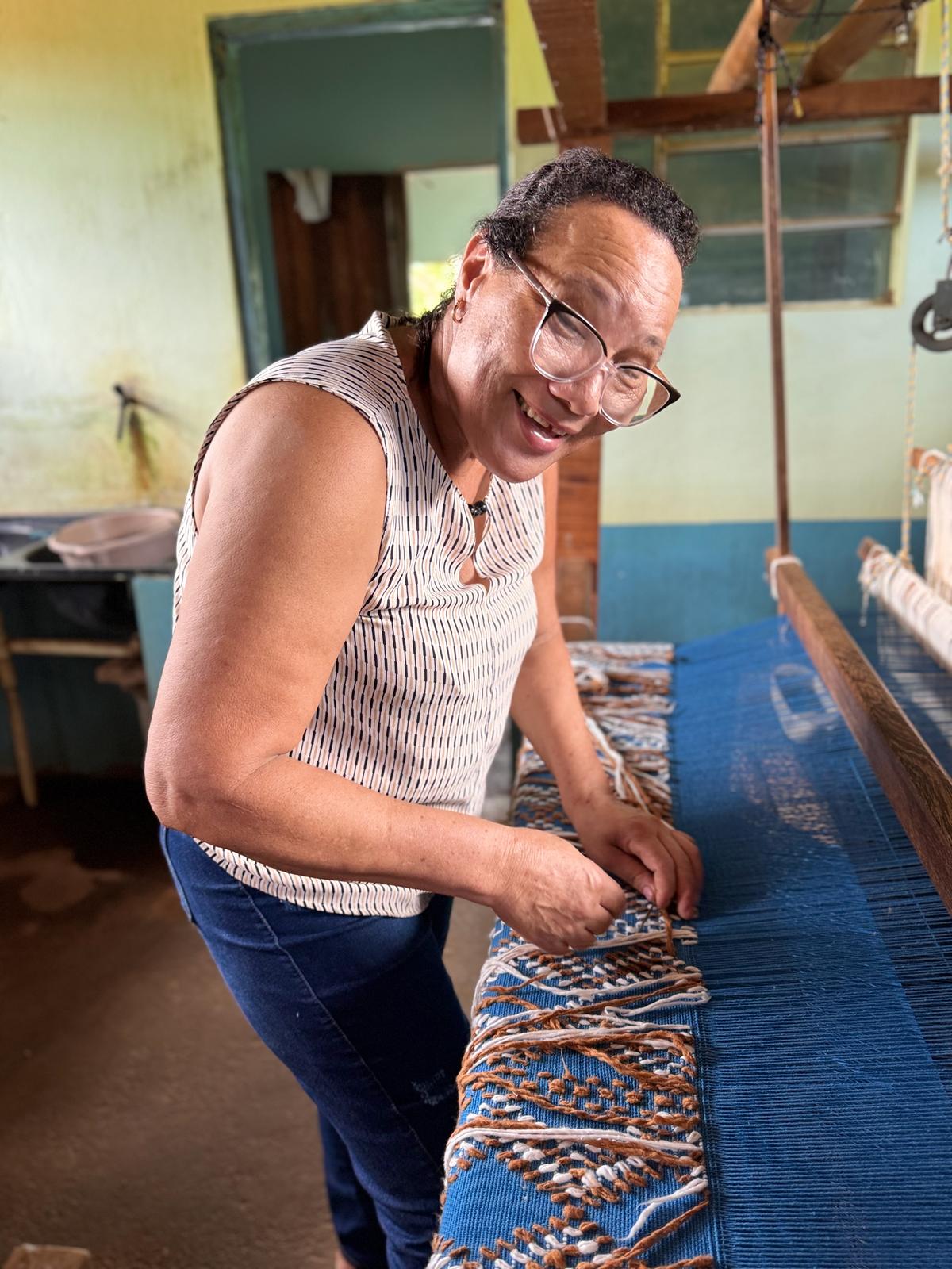 artesã entrelaça os fios que darão vida ao tecido (Maria Fernanda Paes de Barros / Divulgação)