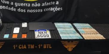 Além do celular do idoso, foram localizados mais cinco aparelhos de procedência duvidosa, com indícios de serem produtos de furto/roubo, cerca de R$ 5 mil em dinheiro, um notebook, cartões de crédito em nome de terceiros e uma placa de motocicleta (Divulgação / PMMG)