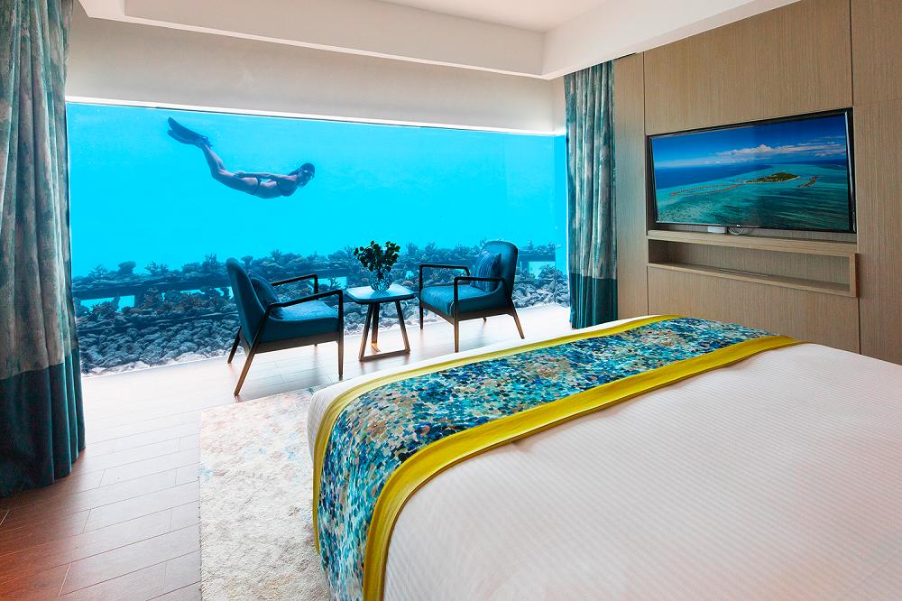 O quarto principal se abre para a vista de um oceano sem fim, com ondas e águas azul-turquesa à frente (Aqua Villas / divulgação)